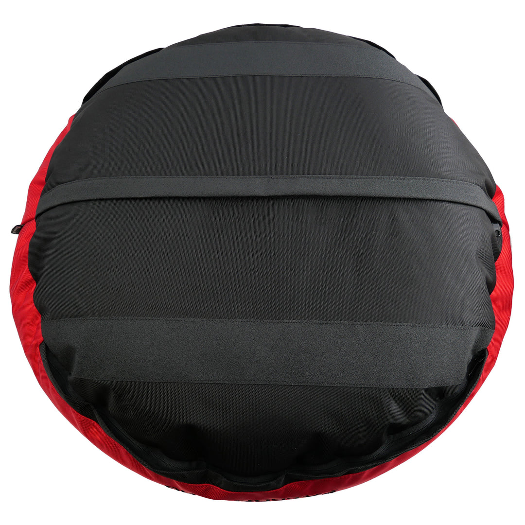 Black bottom of a round bolstered dog bed with black strips and red band