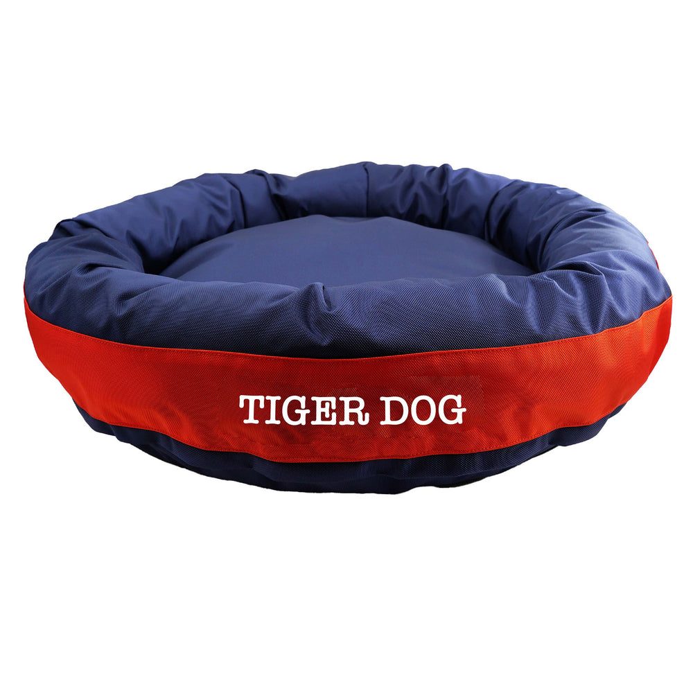 Navy round bolstered dog bed with an orange band and white embroidered 'Tiger Dog'.