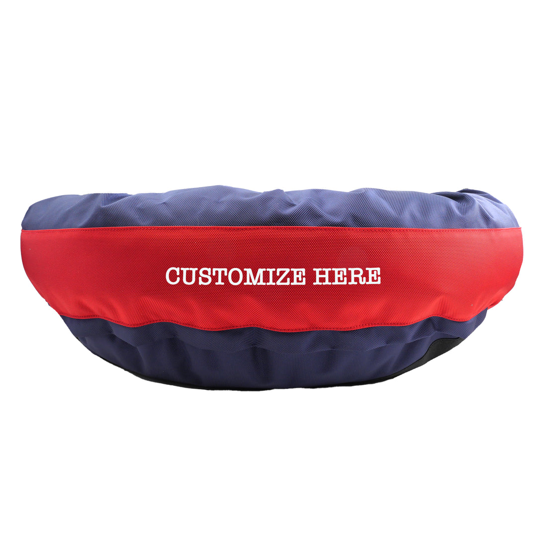 Blue round bolstered dog bed with a red band in the middle with white embroidered 'Customize Here'.
