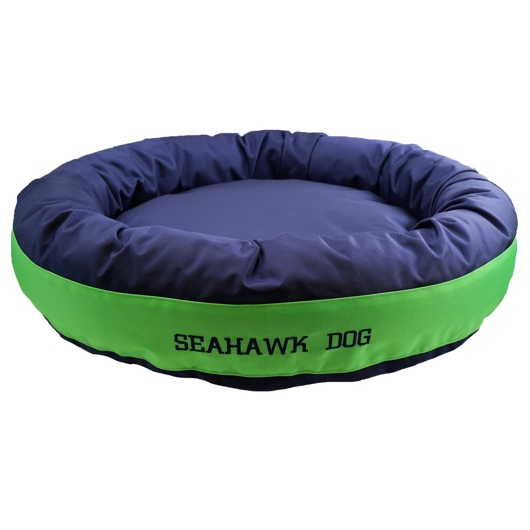 Navy round bolstered dog bed with a green band and blue embroidered 'Seahawk Dog'.