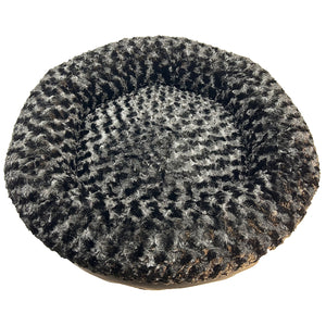 Round bolstered dog bed with textured black fleece surface on a white background