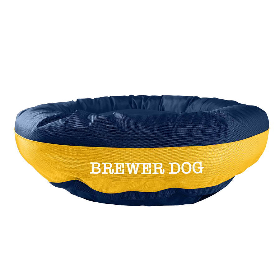 Navy round bolstered dog bed with yellow band in the middle with white embroidered "Brewer Dog'.