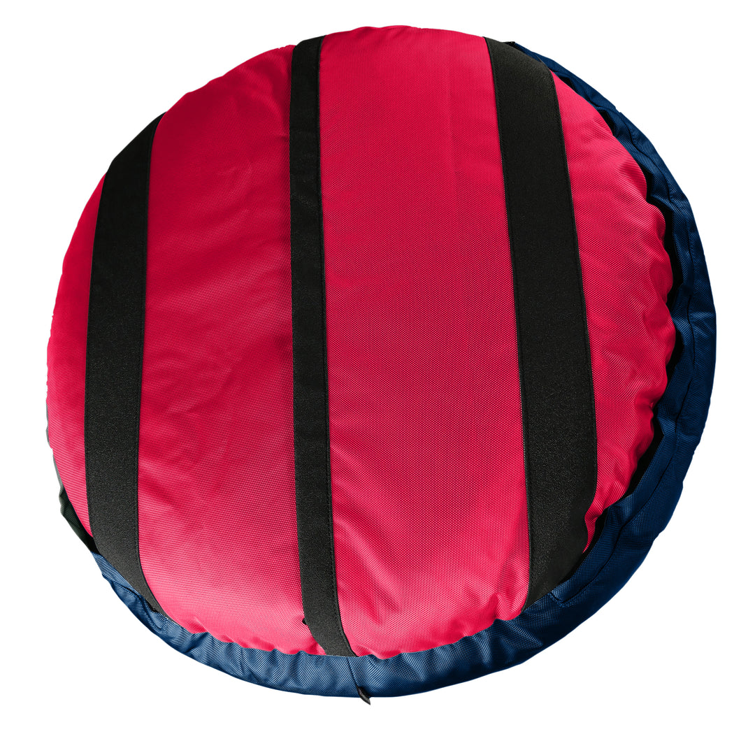 Bottom of a red round bolstered dogg bed with black strips and a navy band.