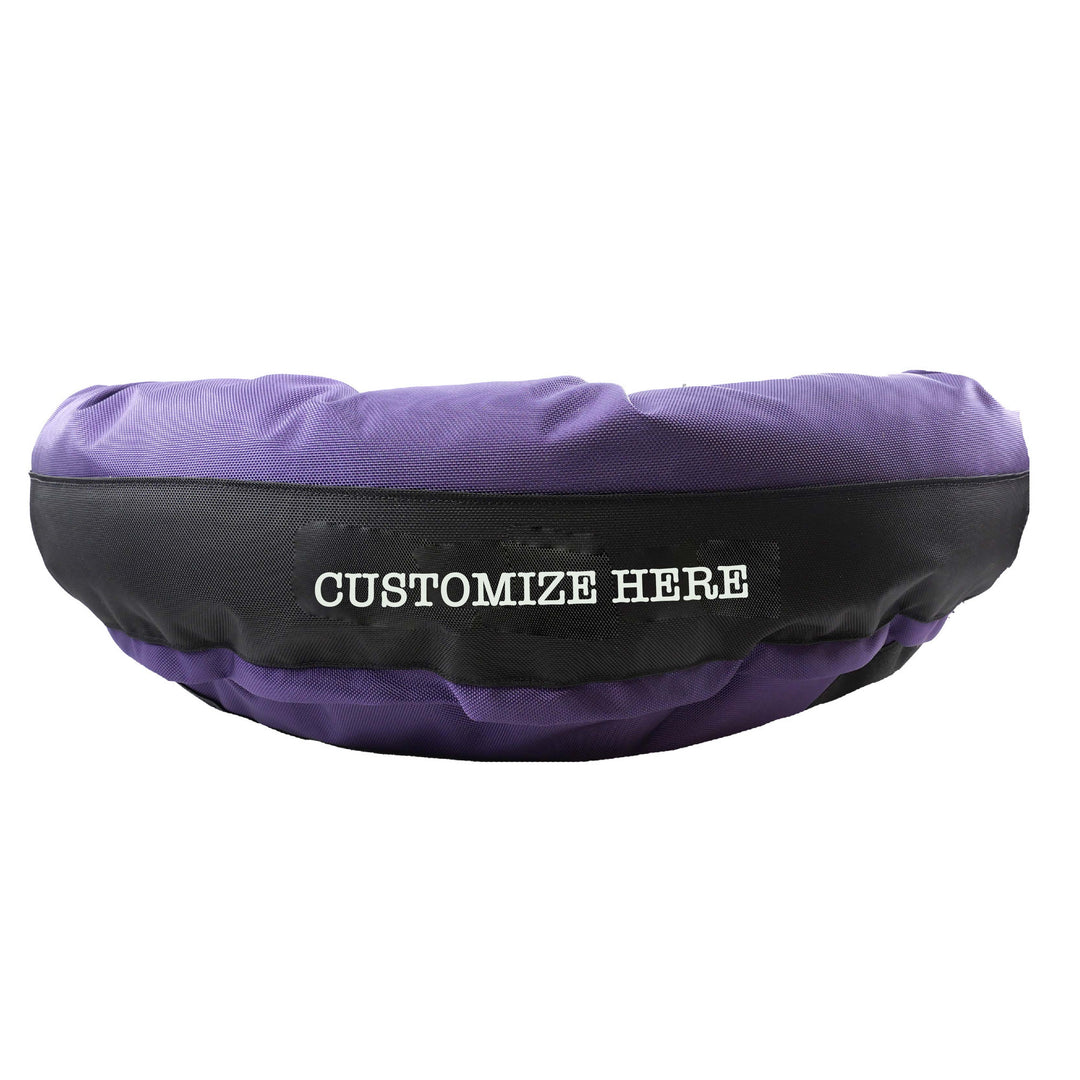 Purple round bolstered dog bed with a black band and white embroidered 'Customize Here'.