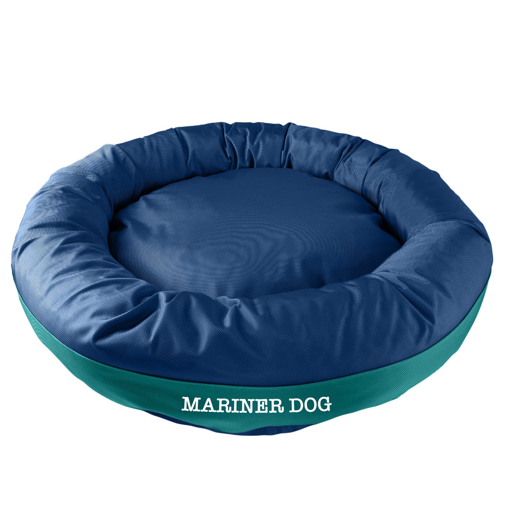 Navy round bolstered dog bed with a teal band and white embroidered 'Mariner Dog'.