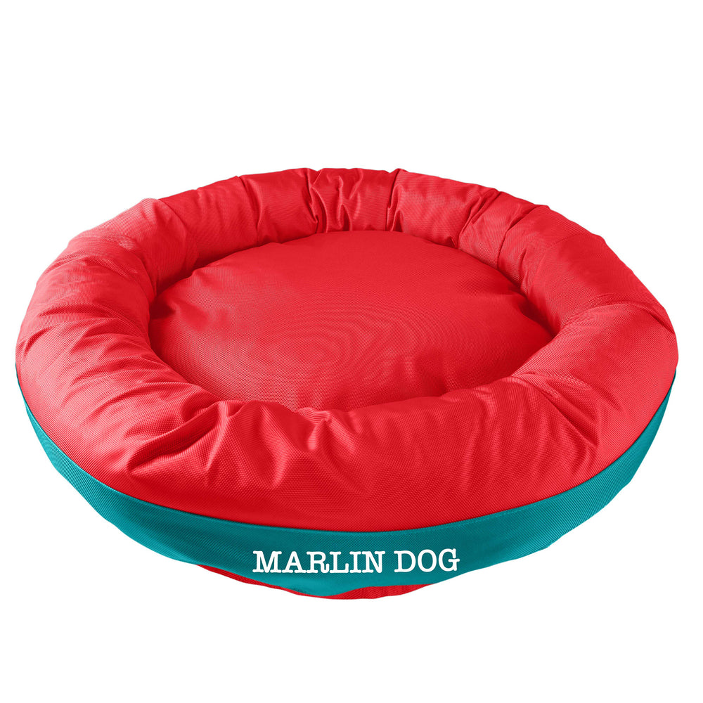 Orange round bolstered dog bed with a teal band and white embroidered 'Marlin Dog'.