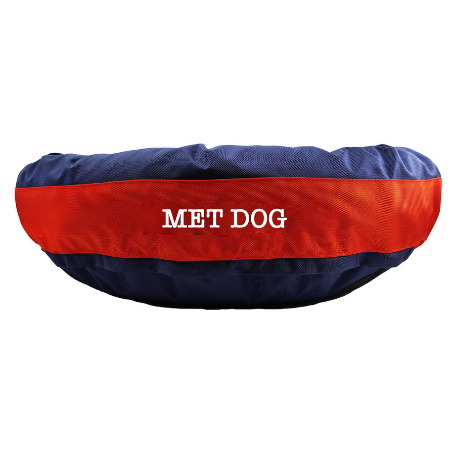 Navy round bolstered dog bed with an orange band and white embroidered 'Met Dog'.