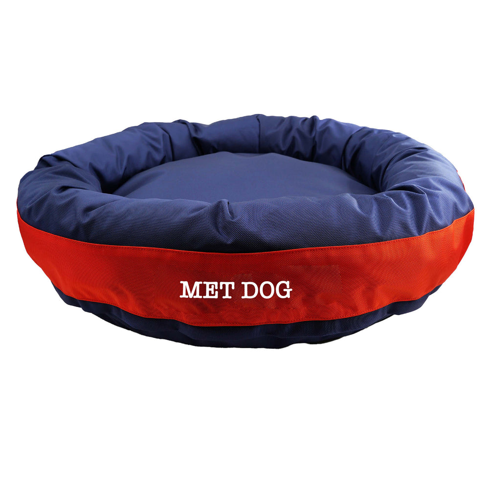 Navy round bolstered dog bed with an orange band and white embroidered 'Met Dog'.