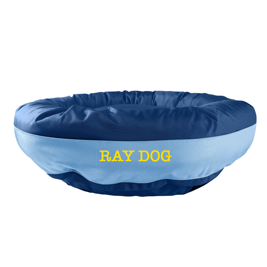 Dark blue round bolstered dog bed with a light blue band and yellow embroidered 'Ray Dog'.