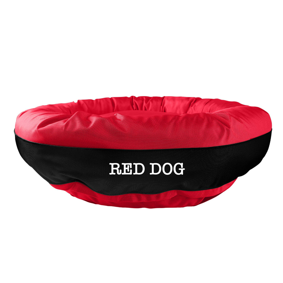 Red round bolstered dog bed with a black band and white embroidered 'Red Dog'.
