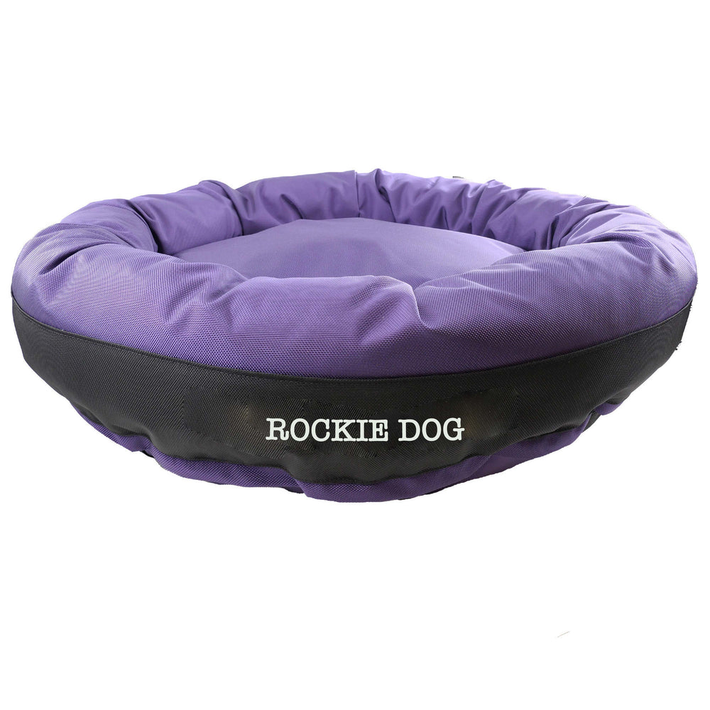 Purple round bolstered dog bed with a black band and white embroidered "Rockie Dog'.