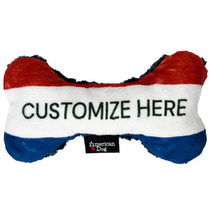 Red, white, and blue  fleece bone-shaped toy with 'Customize Here' text and American Dog brand logo.