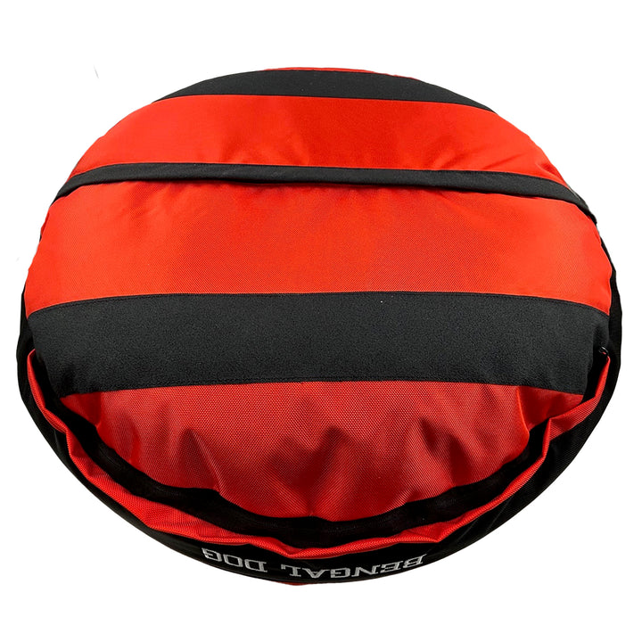 Bottom of an orange round bolstered dog bed with black strips and black band with embroidered 'Bengal Dog'.