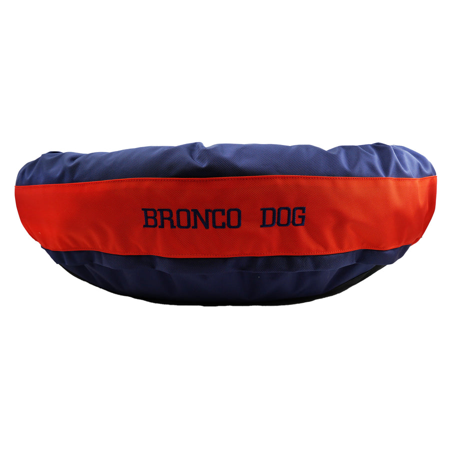 Blue round bolstered dog bed with an orange band with Navy embroidered 'Bronco Dog'.
