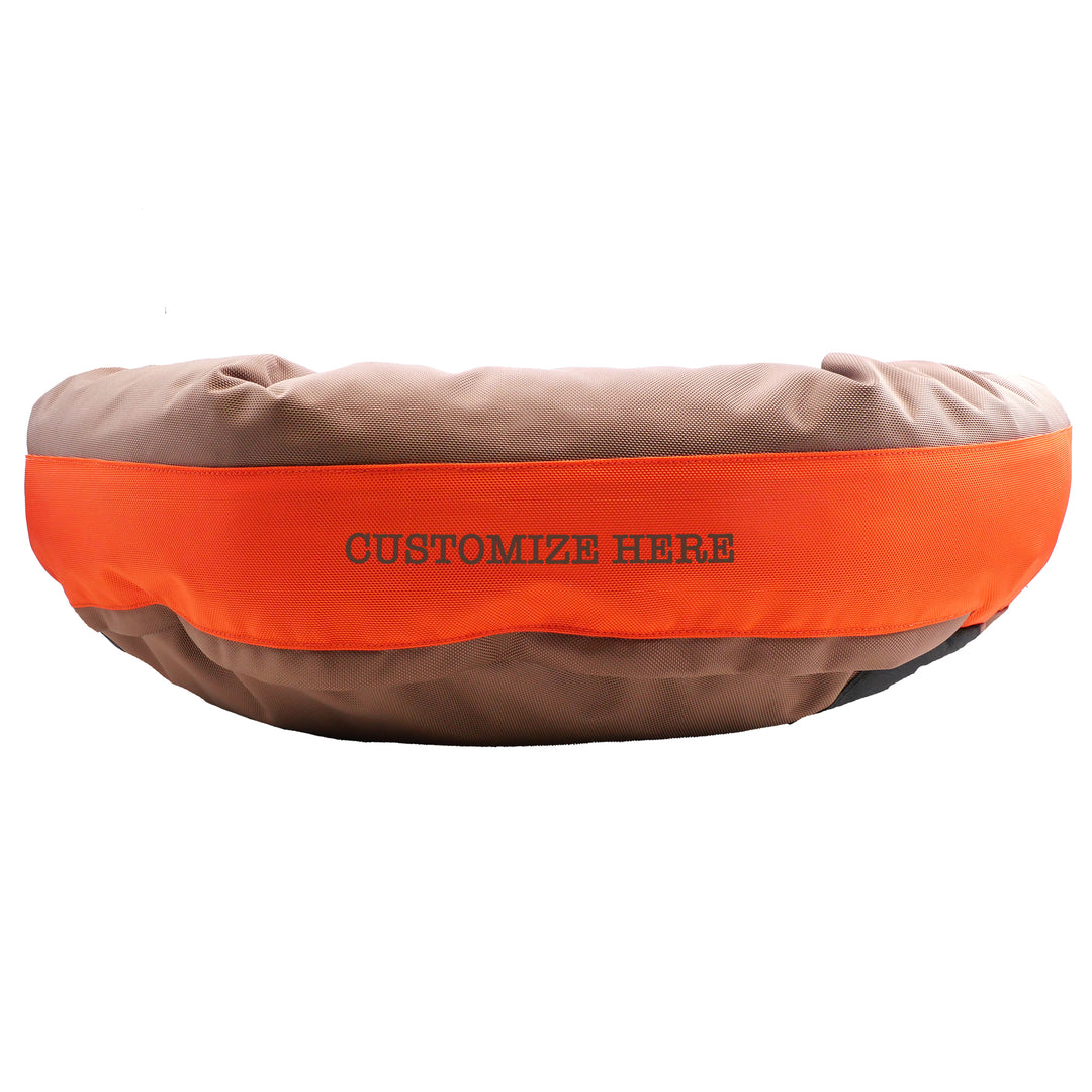 Brown round bolstered dog bed with an orange band and brown embroidered 'Customize Here'.