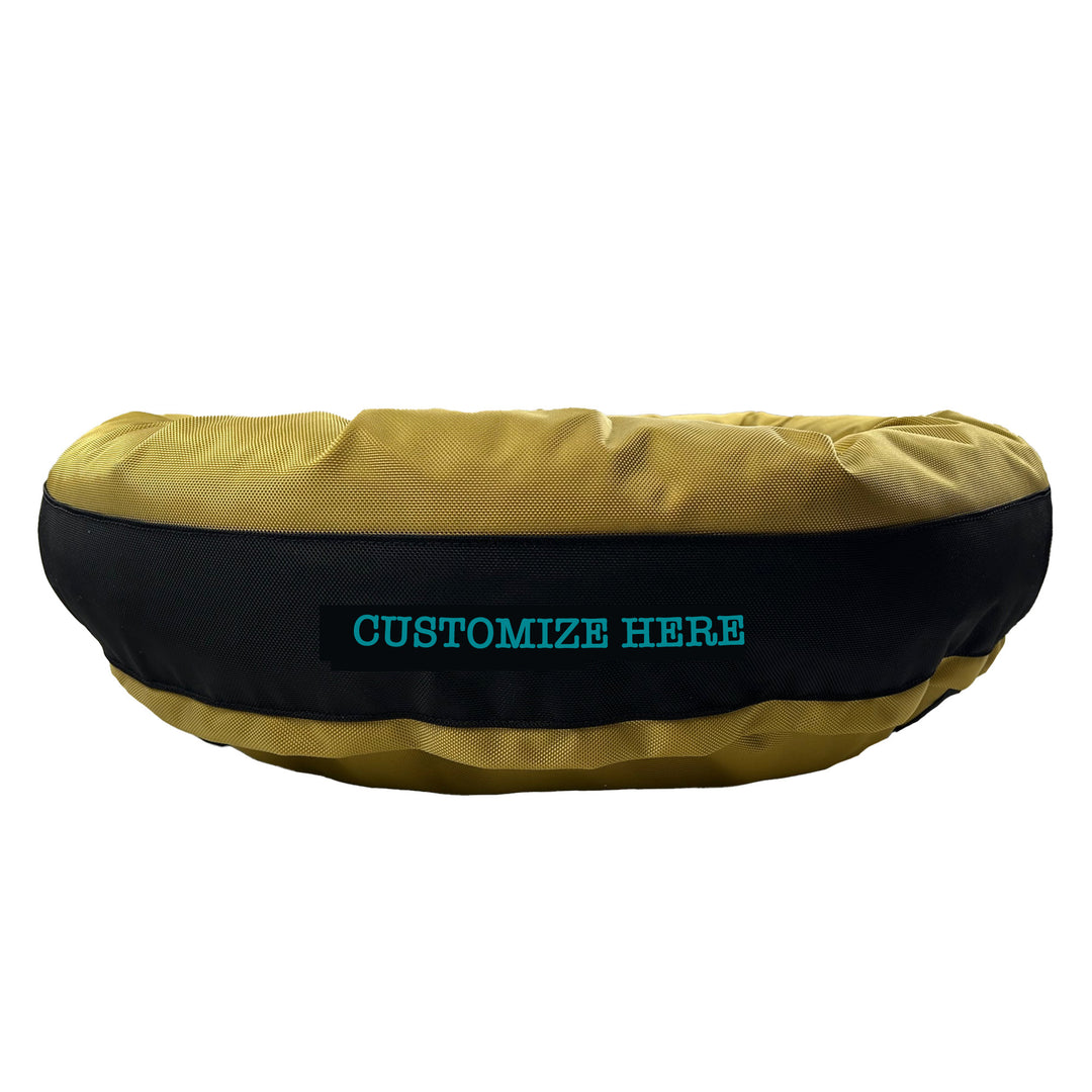 Gold round bolstered dog bed with a black band and teal embroidered 'Customize Here'.