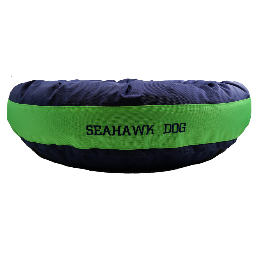 Navy round bolstered dog bed with a green band and blue embroidered 'Seahawk Dog'.