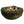 Dog lying on an olive colored round bolstered dog bed with a white background